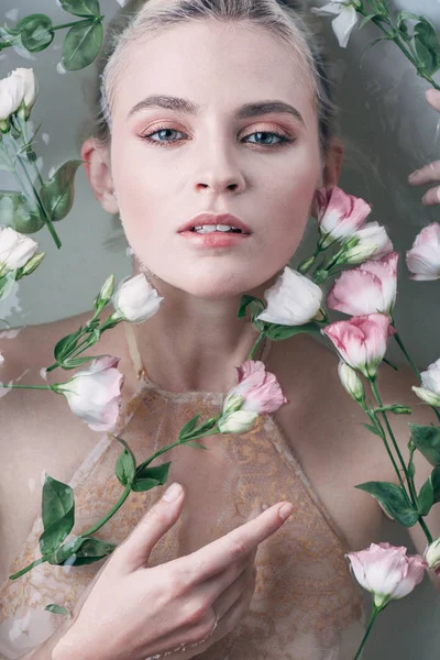 Vue de dessus de la femme sexy en eau claire avec des fleurs dans la baignoire blanche — Photo de stock
