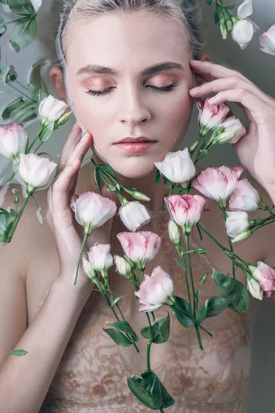 Вид зверху красивої жінки з закритими очима у воді з квітами у білій ванні — стокове фото