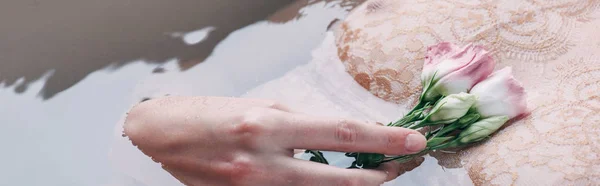 Corte vista de molhado sexy mulher em renda roupa interior segurando flores na água, tiro panorâmico — Fotografia de Stock