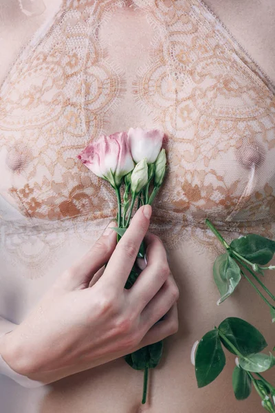 Частковий вид мокрої жінки в мереживній білизні, що тримає квіти — стокове фото