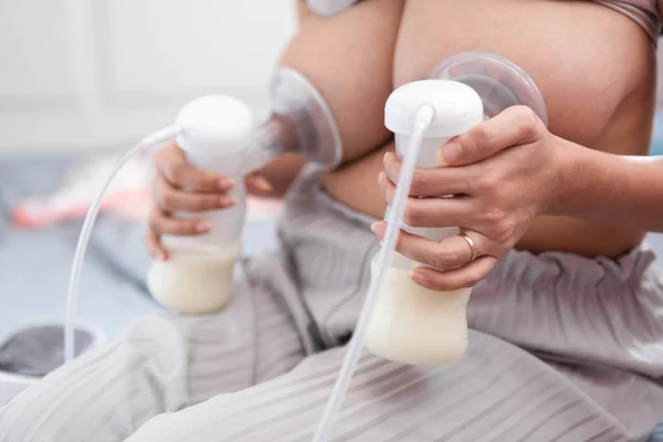 Mladá matka pomocí elektrické prsní pumpy čerpání mateřského mléka. — Stock fotografie