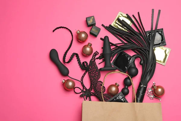 Einkaufstasche und verschiedene Sexspielzeuge auf rosa Hintergrund, flach gelegt — Stockfoto