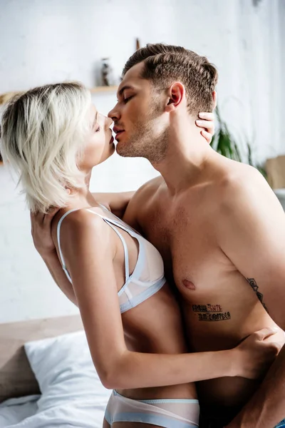 Mulher atraente em roupa interior branca beijando com homem bonito no apartamento — Fotografia de Stock