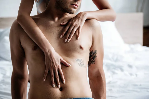 Cropped view of woman hugging shirtless man in apartment — Stock Photo